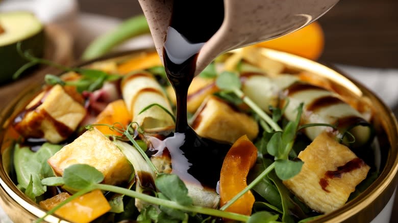 Pouring vinaigrette onto salad