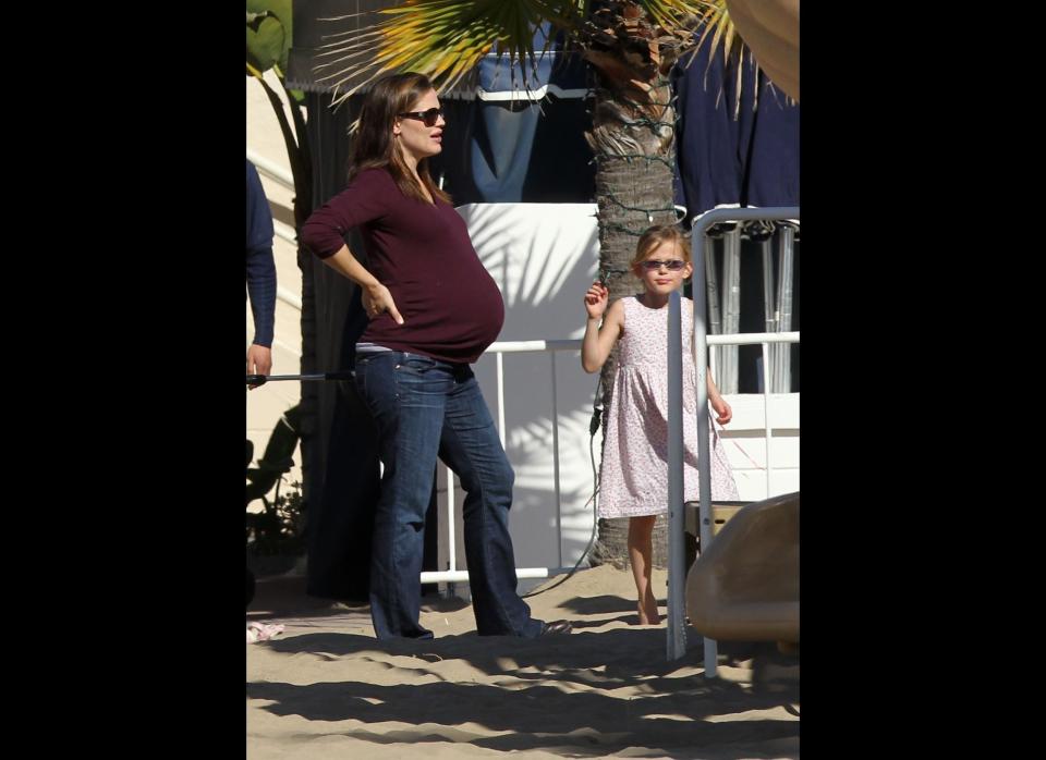 A very pregnant Jennifer Garner supports her back as she looks on at daughter Violet. 