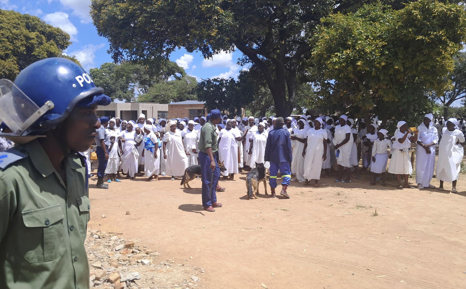 Police with dogs are seen at a shrine on a farm about 34 kilometers (21 miles) north of the capital, Harare, Wednesday, March, 13, 2024. Zimbabwean police on Wednesday said they arrested a man claiming to be a prophet of an apostolic sect at a shrine where believers stay in a compound and authorities found 16 unregistered graves, including those of infants, and more than 250 children used as cheap labor.(AP Photo)