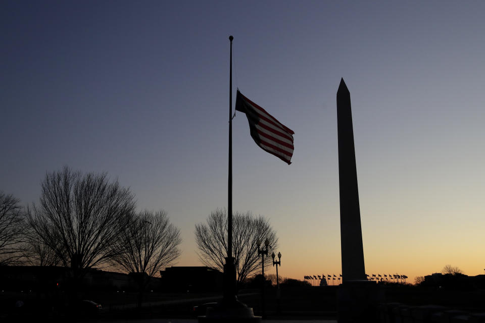 FILE - In this Thursday, Dec. 19, 2019 file photo, a flag at the World War II Memorial flies upside down after it unclipped from its snaphook, before sunrise on Capitol Hill in Washington. At right is the Washington Monument. (AP Photo/Julio Cortez)