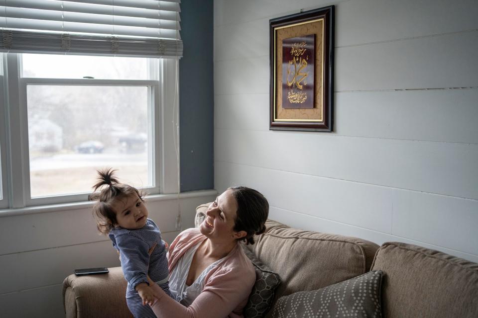 A woman, seated, holds a small child.