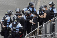 Riot police check the bags of protesters outside the Legislative Council in Hong Kong, Thursday, June 13, 2019. After days of silence, Chinese state media is characterizing the largely peaceful demonstrations in Hong Kong as a "riot" and accusing protesters of "violent acts." (AP Photo/Kin Cheung)