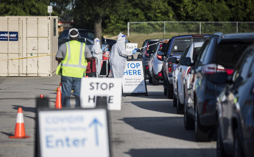 Walmart employees conduct COVID-19 testing for pre-registered individuals in the parking lot of the Ramsey Street Walmart in Fayetteville, N.C., Friday, May 15, 2020. The tests will be processed by eTrueNorth, and are self-administered by the person seeking the test in their car with their window up. (Julia Wall/The News & Observer via AP)