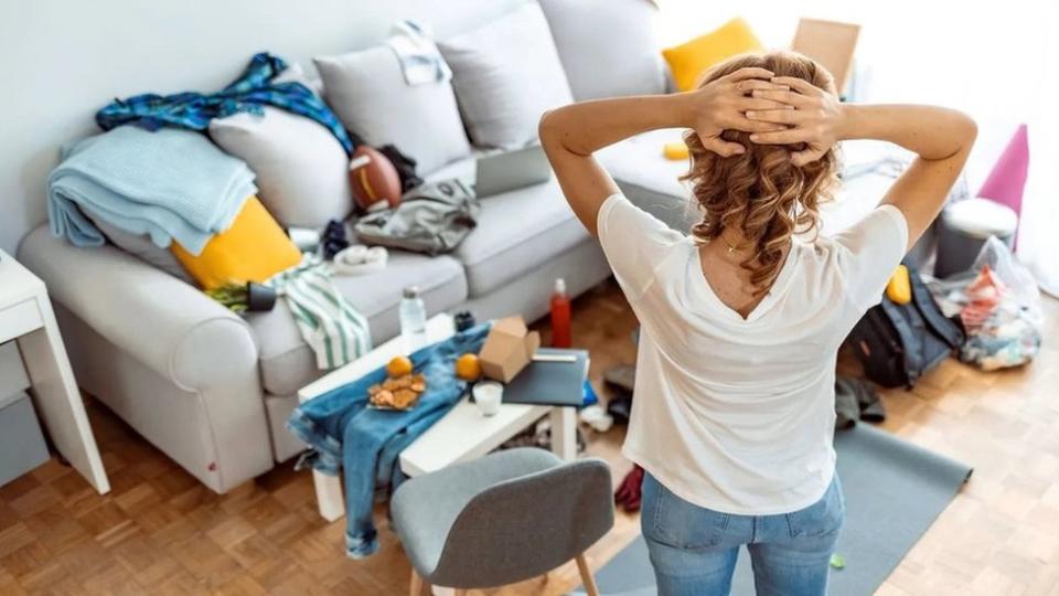 Una mujer observa su casa desordenada.