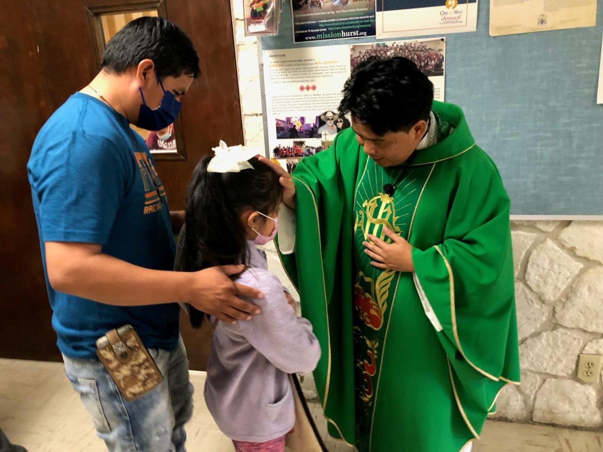 Father Ryan Carnecer prays with a family after Sunday mass at Divine Providence Catholic Church in San Antonio.