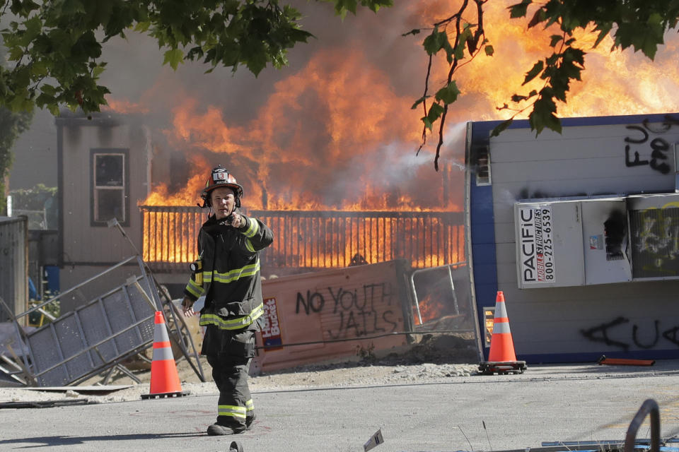 Construction buildings burn near the King County Juvenile Detention Center, Saturday, July 25, 2020, in Seattle, shortly after a group of protesters left the area. A large group of protesters were marching Saturday in Seattle in support of Black Lives Matter and against police brutality and racial injustice. Protesters broke windows and vandalized cars at the facility. (AP Photo/Ted S. Warren)