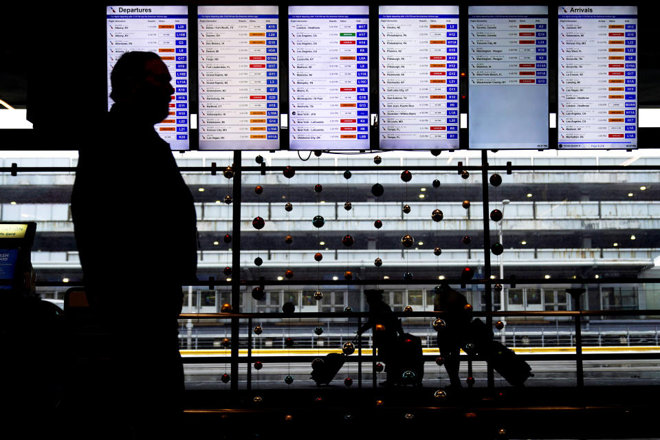 Travelers walk past flight information screens displaying flight status information at O'Hare International Airport in Chicago, Thursday, Dec. 22, 2022. (AP Photo/Nam Y. Huh)