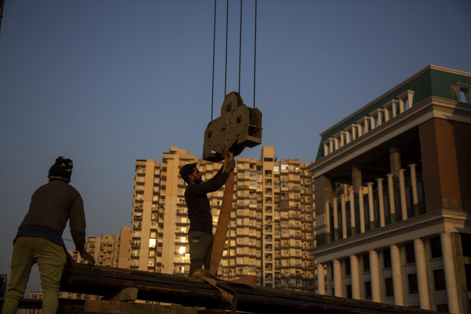 FILE - Workers handle building construction materials in Greater Noida, India, on Dec. 7, 2022. China’s recovery from the pandemic and strong demand in India will drive strong growth in Asia this year, the Asian Development Bank said in a report issued Tuesday, April 4, 2023. (AP Photo/Bhumika Saraswati, File)