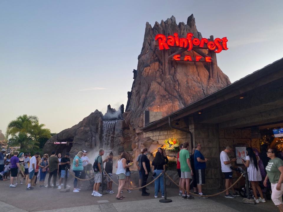 A line of people wait to enter the Rainforest Cafe at Disney Springs in July 2022.