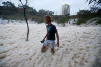 A man walks through ocean foam in Snapper Rocks as Queensland experiences severe rains and flooding from Tropical Cyclone Oswald on January 28, 2013 in Gold Coast, Australia. Hundreds have been evacuated from the towns of Gladstone and Bunderberg while the rest of Queensland braces for more flooding. (Photo by Chris Hyde/Getty Images)