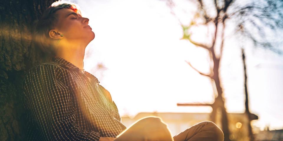 A person meditating against a tree.