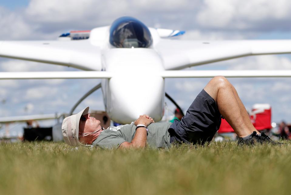 A man rests in front of an airplane July 29 at EAA AirVenture Oshkosh.