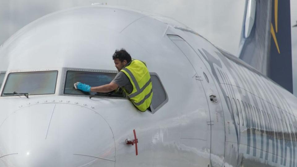 Un trabajador limpiando las ventanas de un avión