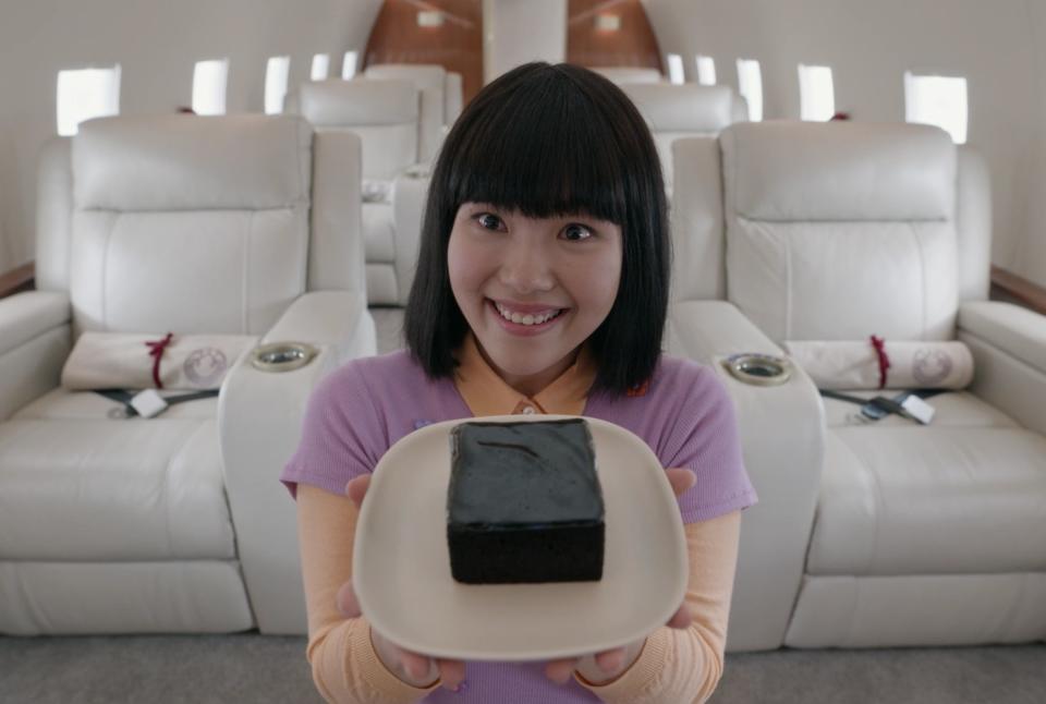 Linh holding a piece of cake on the plane in "The Wilds"