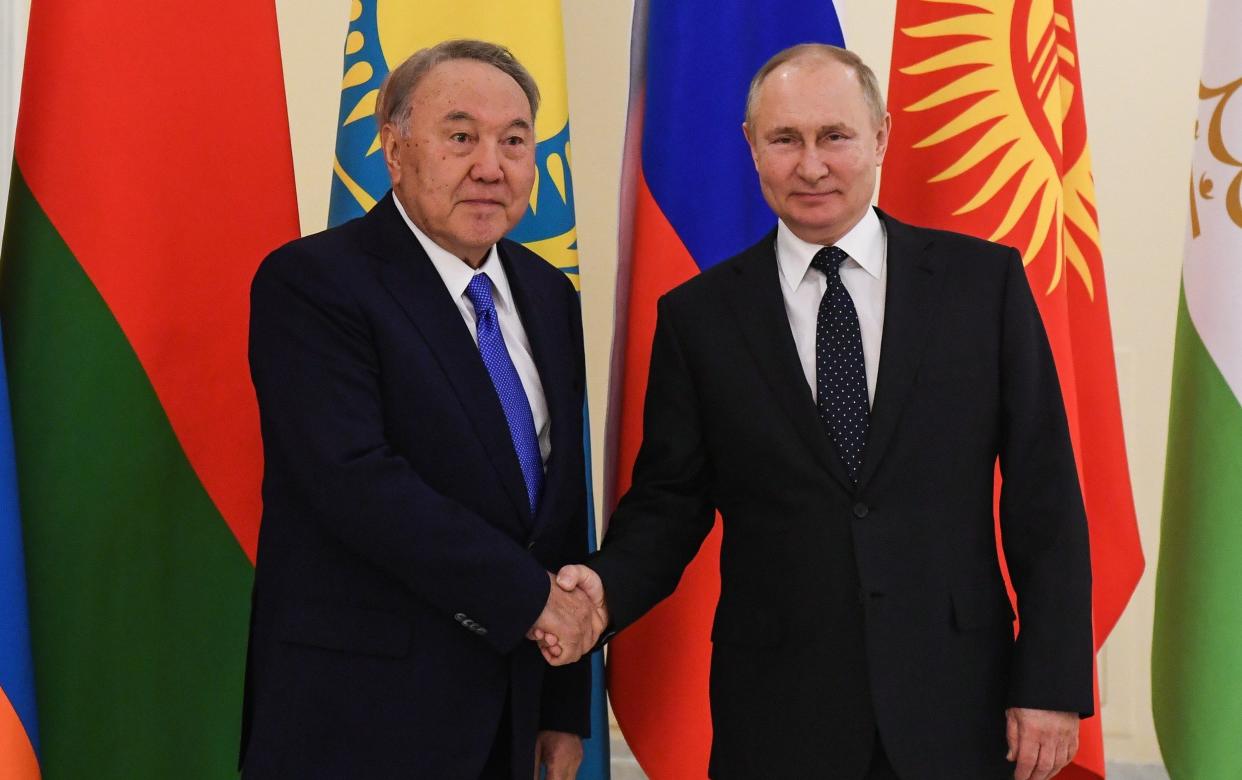 Kazakhstan's former president Nursultan Nazarbayev (L) and Russia's President Vladimir Putin shake hands during a meeting on the sidelines of an informal CIS summit at the Boris Yeltsin Presidential Library - Yevgeny Biyatov/TASS