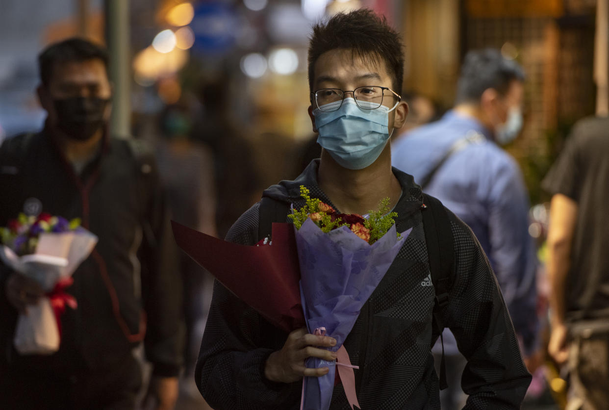 HONG KONG, CHINA - FEBRUARY 14, 2020: Customers carry flowers during Valentine's Day wearing a face mask as a preventative measure against the COVID-19. As of Friday, the death toll from China's coronavirus virus epidemic surpassed 1,400 and 60,000 infected  after new reporting methods were adopted.- PHOTOGRAPH BY Miguel Candela / Echoes Wire/ Barcroft Media (Photo credit should read Miguel Candela / Echoes Wire/Barcroft Media via Getty Images)