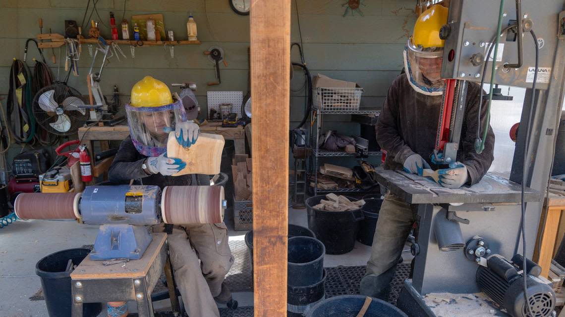 Meaghan Goulder sands a cutting board and Mike Goulder uses a band saw to cut out spatulas at their home workshop Thursday in Boise.