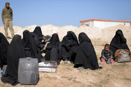 FILE PHOTO: Women sit together with their belongings near Baghouz, Deir Al Zor province, Syria February 12, 2019. Picture taken February 12, 2019. REUTERS/ Rodi Said/File Photo