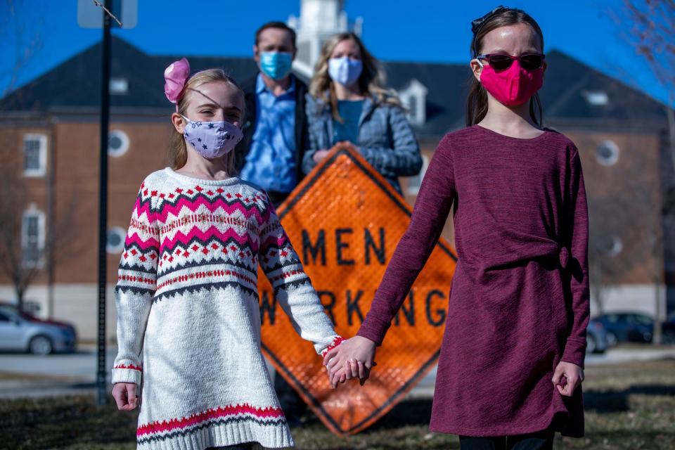 Brienne Babione (left), 9, stands with her sister Blair Babione, 11, as their parents John and Leslie Babione stand in the background, Tuesday, March 2, 2021, a day after the girls visited Carmel City Hall hoping to convince the city to abandon the gendered signage it uses. 