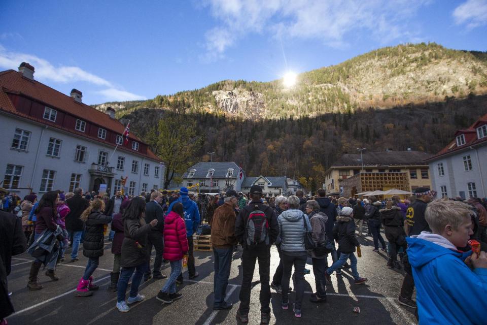 A crowd forms, those in the centre bathing in sunlight, for the official opening of giant sun mirrors in the town of Rjukan, Norway, Wednesday, Oct. 30, 2013. Residents of the small Norwegian town of Rjukan have finally seen the light. Tucked in between steep mountains, the town is normally shrouded in shadow for almost six months a year. But on Wednesday faint rays from the winter sun for the first time reached the market square thanks to three 183-square-foot (17-square-meter) mirrors placed on a mountain. (AP Photo/NTB Scanpix, Terje Bendiksby) NORWAY OUT