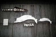 Sign boards featuring Baird's beaked whale are displayed at the entrance of a restaurant P-man in Minamibos