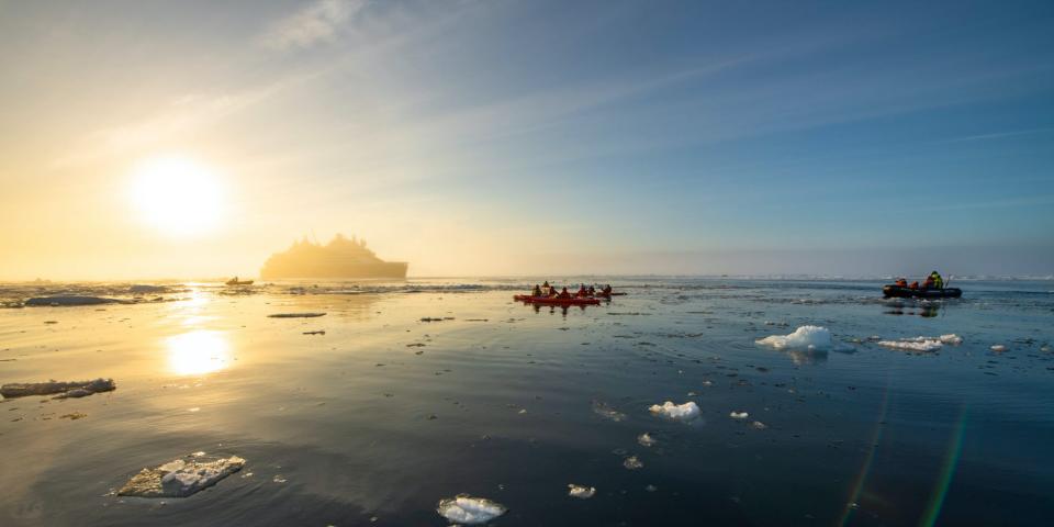 kayakers on icy water with the Le Commandant Charcot in the back