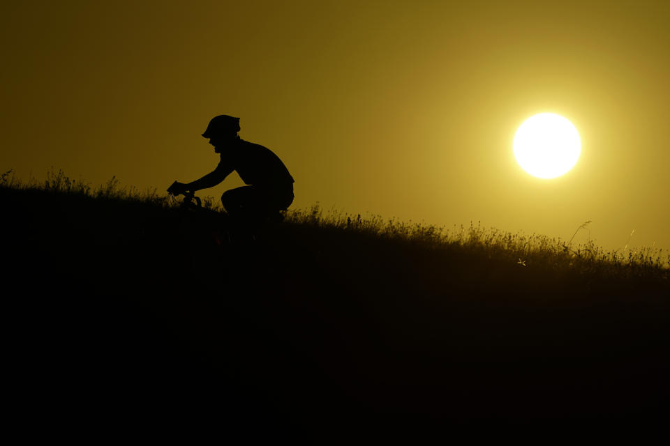 A cyclist moves up a hill during sunset, Monday, July 17, 2023, in San Antonio. Triple-digit temperatures and heat advisories are expected throughout the week. (AP Photo/Eric Gay)