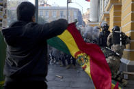 A supporter of President Luis Arce waves a Bolivian flag as soldiers flee from Plaza Murillo, after a failed coup attempt, in La Paz, Bolivia, Wednesday, June 26, 2024. Armored vehicles rammed into the doors of Bolivia's government palace located in Plaza Murillo as Arce said the country faced an attempted coup. (AP Photo/Juan Karita)