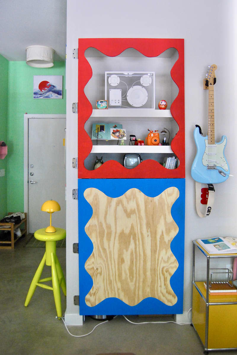 Scalloped frame surrounds shelves in art filled apartment.