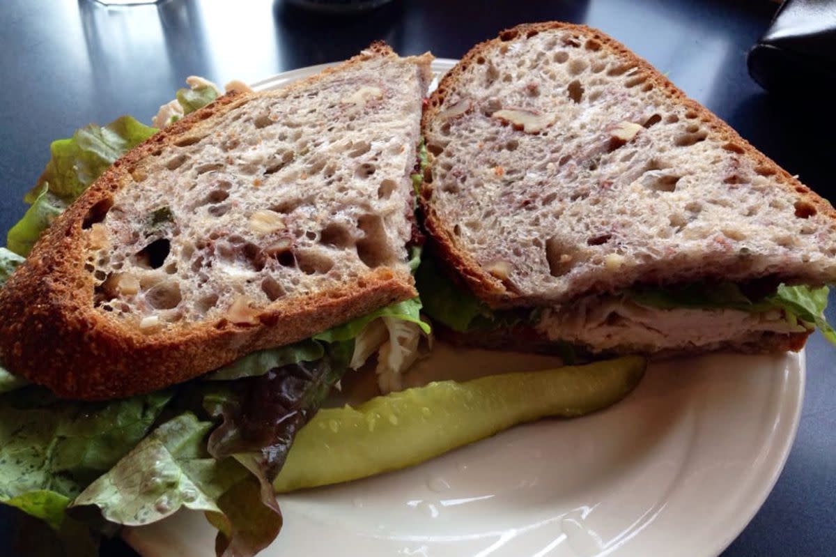 Spicy Tuna Melt Sandwich with a slice of pickle on a white ceramic plate, WheatFields, Lawrence, Kansas, on a shiny black table