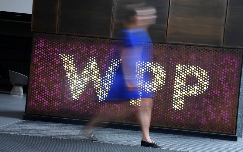 A woman walks past signage for WPP Group, the largest global advertising and public relations agency at their offices in London