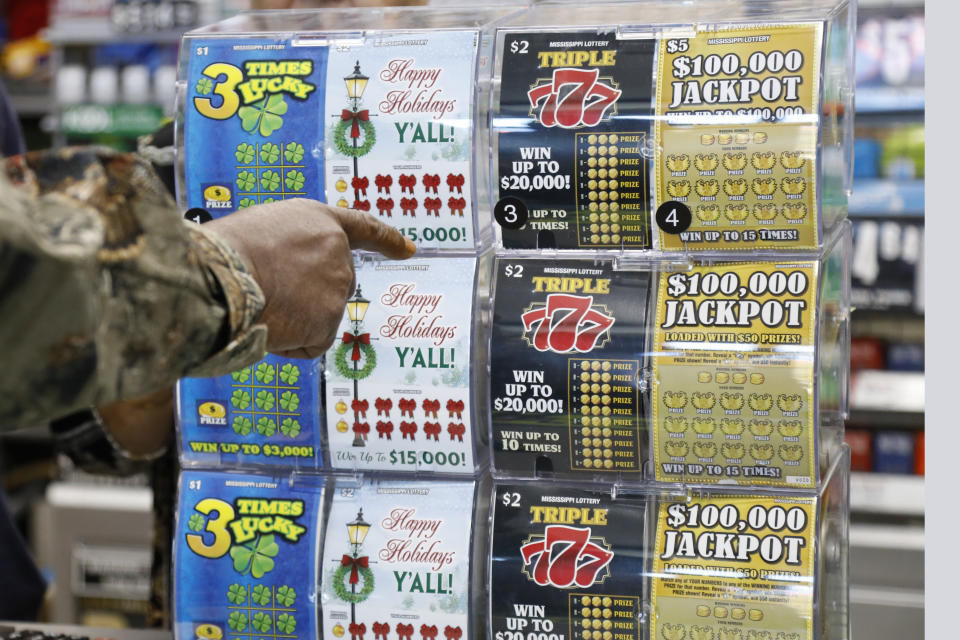 A customer points to the scratch-off ticket she wants to purchase from at a Jackson, Miss., convenience store, Monday, Nov. 25, 2019. Licensed lottery retailers in the state began selling tickets Monday for the first time in the state. The multistate games Powerball and Mega Millions will be available in Mississippi starting Jan. 30. (AP Photo/Rogelio V. Solis)