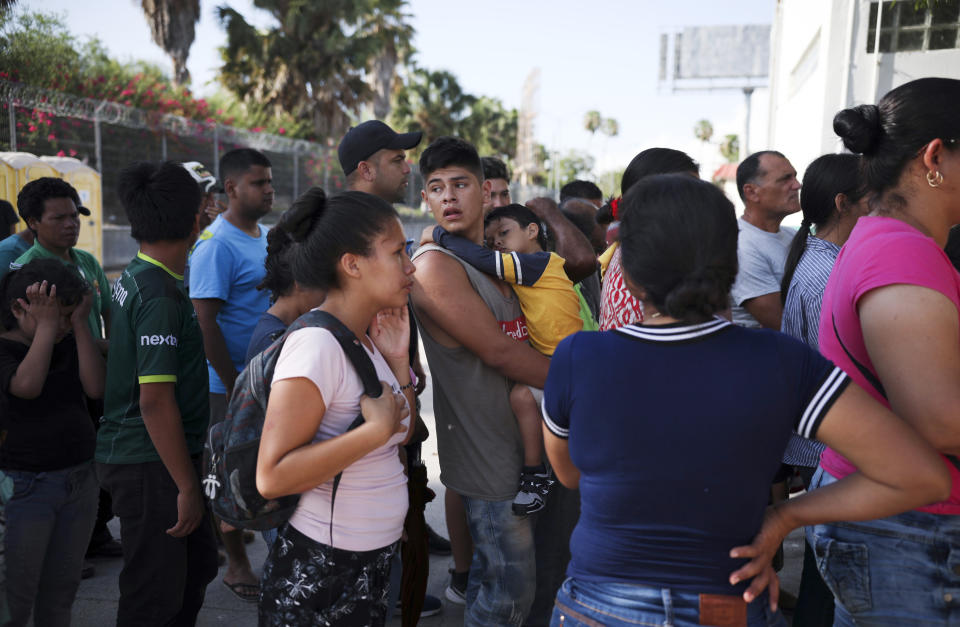 Archivo - En esta fotografía de archivo del 1 de agosto de 2019, migrantes hacen fila en Matamoros, México, para recibir una comida donada por voluntarios estadounidenses, en el puente Puerto México que cruza hacia Brownsville, Texas. (AP Foto/Emilio Espejel. Archivo)