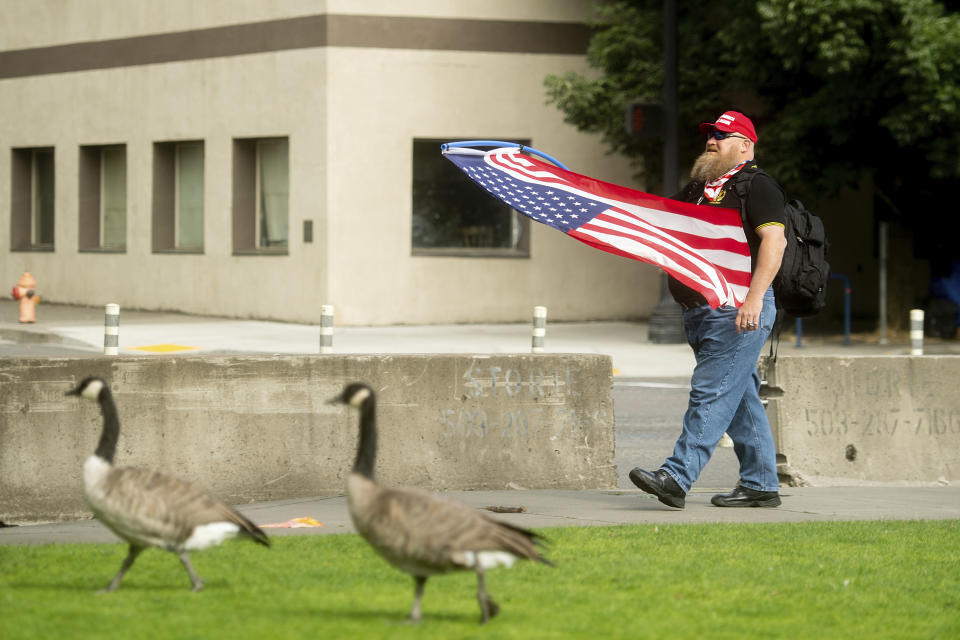 A member of the Proud Boys, who declined to give his name, carries a flag before the start of a protest in Portland, Ore., on Saturday, Aug. 17, 2019. Police have mobilized to prevent clashes between conservative groups and counter-protesters who plan to converge in the city. (AP Photo/Noah Berger)