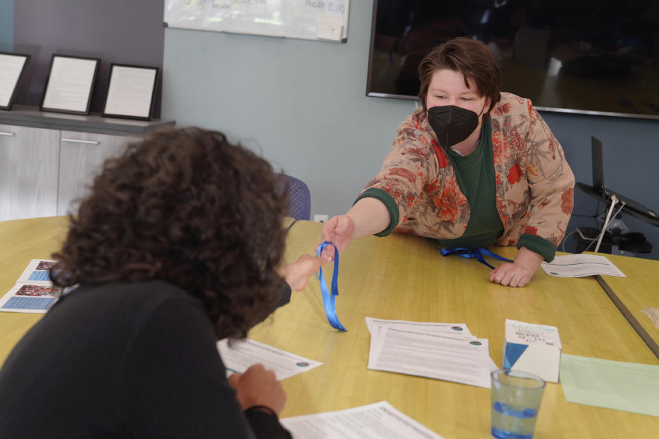 Jess Gold, program manager with Repair the World Pittsburgh, left, takes a blue ribbon to wear in solidarity with the families and congregations of the victims of the 2018 Pittsburgh synagogue massacre, at the conclusion of a Community Gardening Program, Chai Chai V'kayam, or "live, live and be sustained," hosted by Repair the World and the 10.27 Healing Partnership, on Tuesday April 18, 2023, in Pittsburgh, Pa. (AP Photo/Jessie Wardarski)