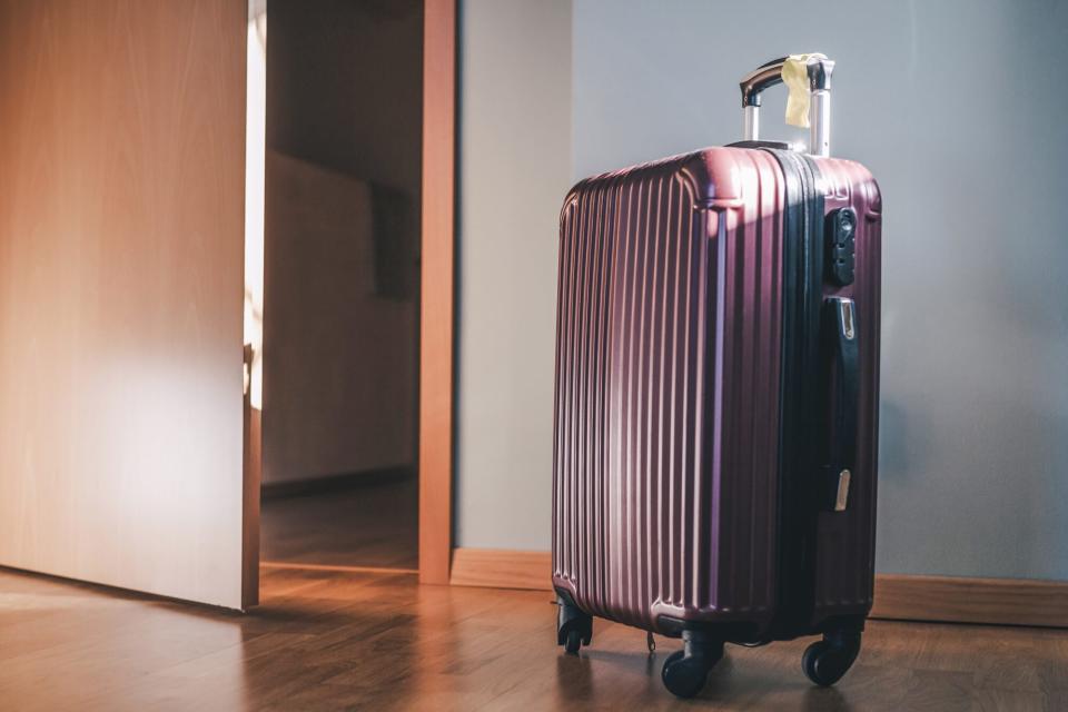 A plastic suitcase standing on a floor in a room
