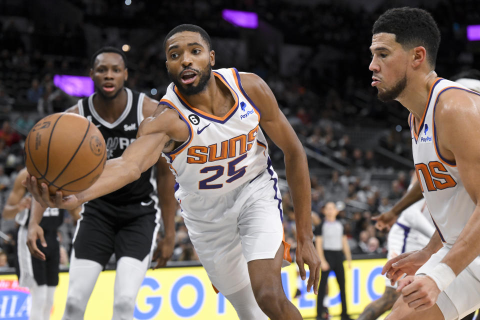 Phoenix Suns' Mikal Bridges (25) grabs the loose ball ahead of San Antonio Spurs' Charles Bassey, left, as Suns' Devin Booker watches during the second half of an NBA basketball game, Sunday, Dec. 4, 2022, in San Antonio. (AP Photo/Darren Abate)