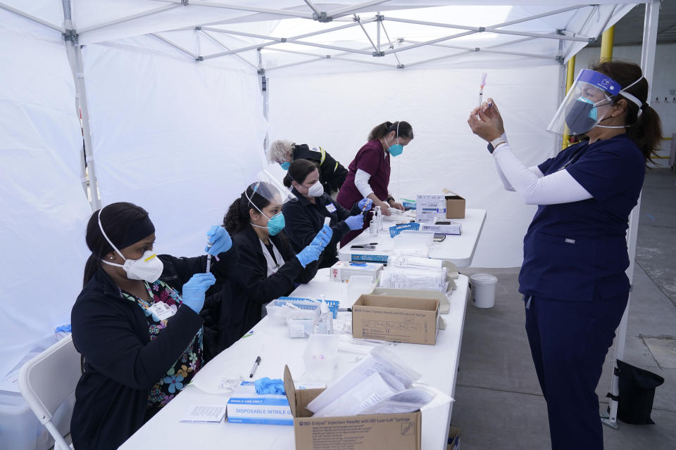 FILE - In this March 3, 2021, file photo, public health nurse Dyah Moore, right, and other health care workers prepare Moderna COVID-19 vaccines for farmworkers at a County of Santa Clara mobile vaccination clinic at Monterey Mushrooms, an agricultural employer under the United Farm Workers union contract, amid the coronavirus pandemic in Morgan Hill, Calif. In some California counties, vaccination drives are targeting farmworkers. (AP Photo/Jeff Chiu, File)