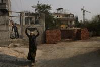 A construction laborer works nearby where employees of Solar Square are putting panels on the rooftop of a residence in Gurugram on the outskirts of New Delhi, India, Tuesday, Feb. 20, 2024. India is renewing its push to add rooftop solar to meet the needs of a fast-growing nation that's hungry for energy. (AP Photo/Manish Swarup)