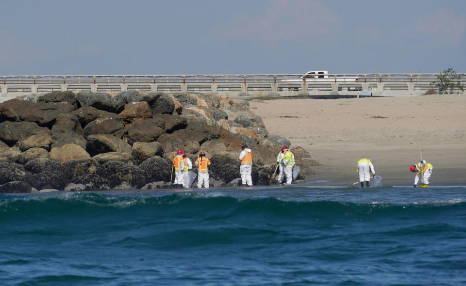 Cleanup crews walking along the beach inspect beach areas and retrieve oil spill debris deposited in Huntington Beach, Calif., Tuesday, Oct. 5, 2021. An oil spill sent up to 126,000 gallons of heavy crude into the ocean. It contaminated the sands of famed Huntington Beach and other coastal communities. (AP Photo/Eugene Garcia)