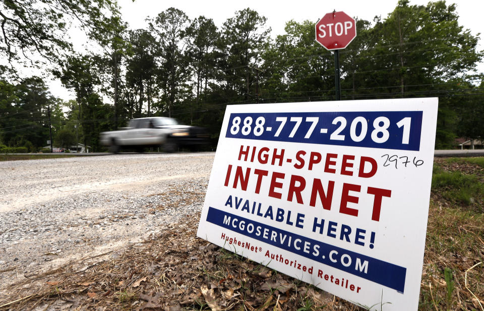 In this May 8, 2019, photo, a car drives past a sign advertising high-speed internet service near Starkville, Miss. In classrooms, access to laptops and the internet is nearly universal. But many students struggle to keep up from home because of the cost of internet service and gaps in its availability. (AP Photo/Rogelio V. Solis)