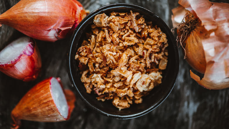 Fried onions in bowl with fresh onions in background