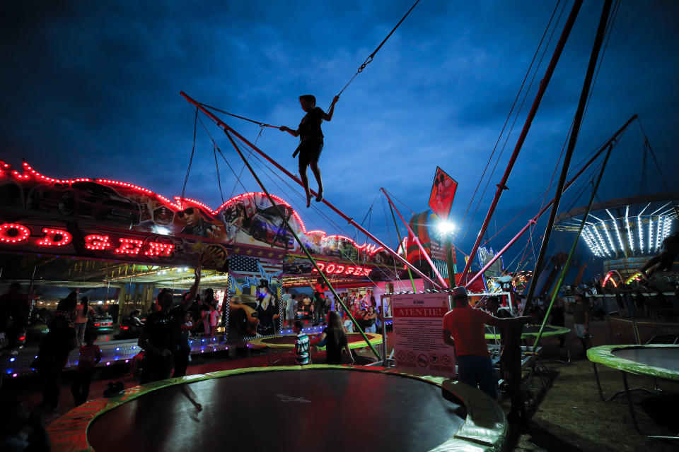 In this picture taken Saturday, Sept. 14, 2019, a child jumps on a trampoline at an autumn fair in Titu, southern Romania. Romania's autumn fairs are a loud and colorful reminder that summer has come to an end and, for many families in poorer areas of the country, one of the few affordable public entertainment events of the year. (AP Photo/Vadim Ghirda)