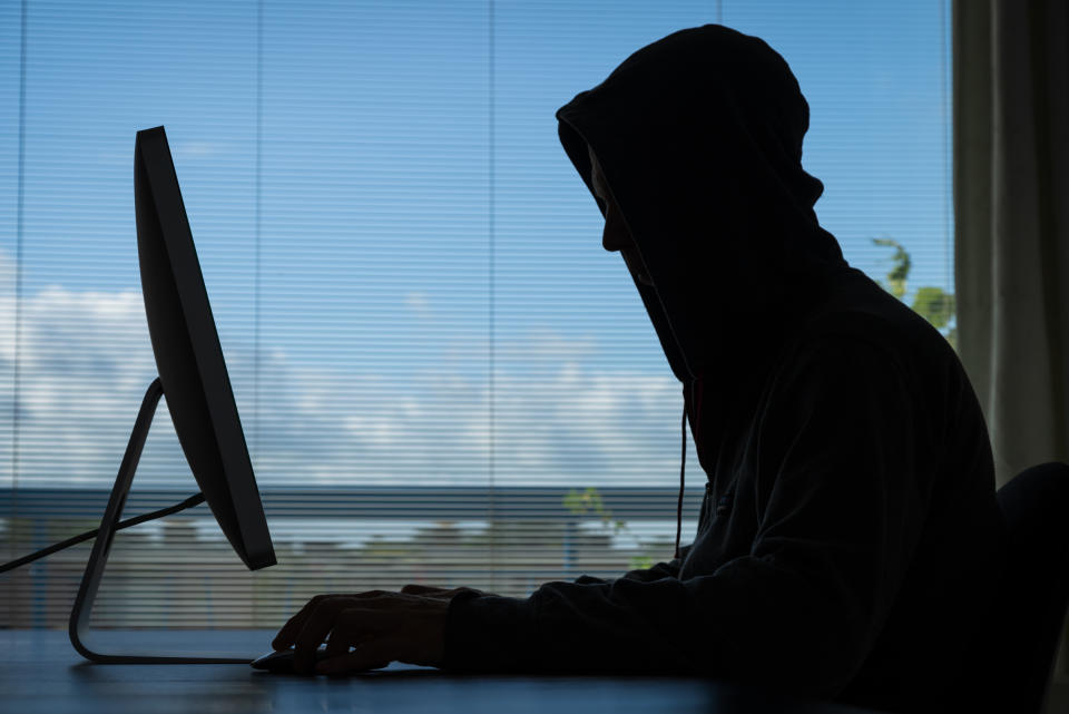 A youth in a hoodie at a desktop computer. 