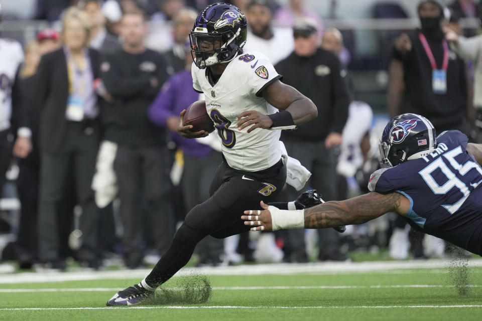 Baltimore Ravens quarterback Lamar Jackson (8) runs the ball past Tennessee Titans defensive tackle Kyle Peko (95) during the second half of an NFL football game Sunday, Oct. 15, 2023, at the Tottenham Hotspur stadium in London. (AP Photo/Kin Cheung)