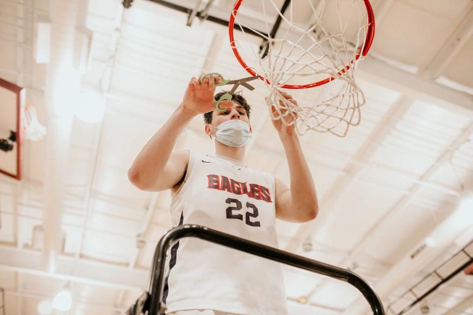 Lincoln Charter senior center Carter Seitz helps cut down the net after the school won the 1A Western Regional Final on Tuesday with a 64-54 victory over Mount Airy.