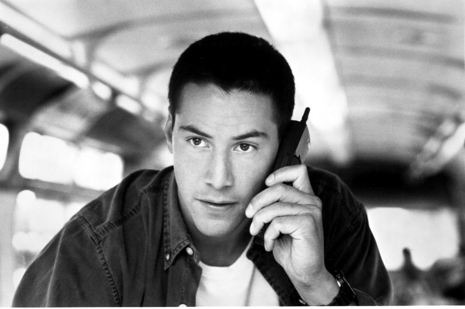 Keanu uses a cell phone on the bus