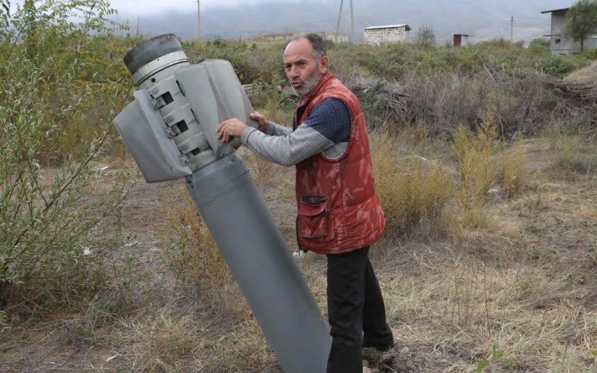 A man poses with an unexploded rocket shell - AFP VIA GETTY