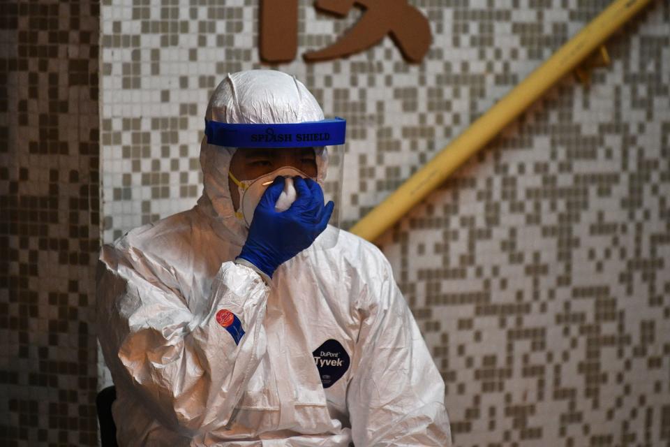 A medical personnel wearing a protective suit checks his mask as he waits near a block's entrance in the ground of a residential estate, in Hong Kong, early on February 11, 2020, after two people in the block were confirmed to have contracted the coronavirus according to local newspaper reports. (Photo by Anthony WALLACE / AFP) (Photo by ANTHONY WALLACE/AFP via Getty Images)