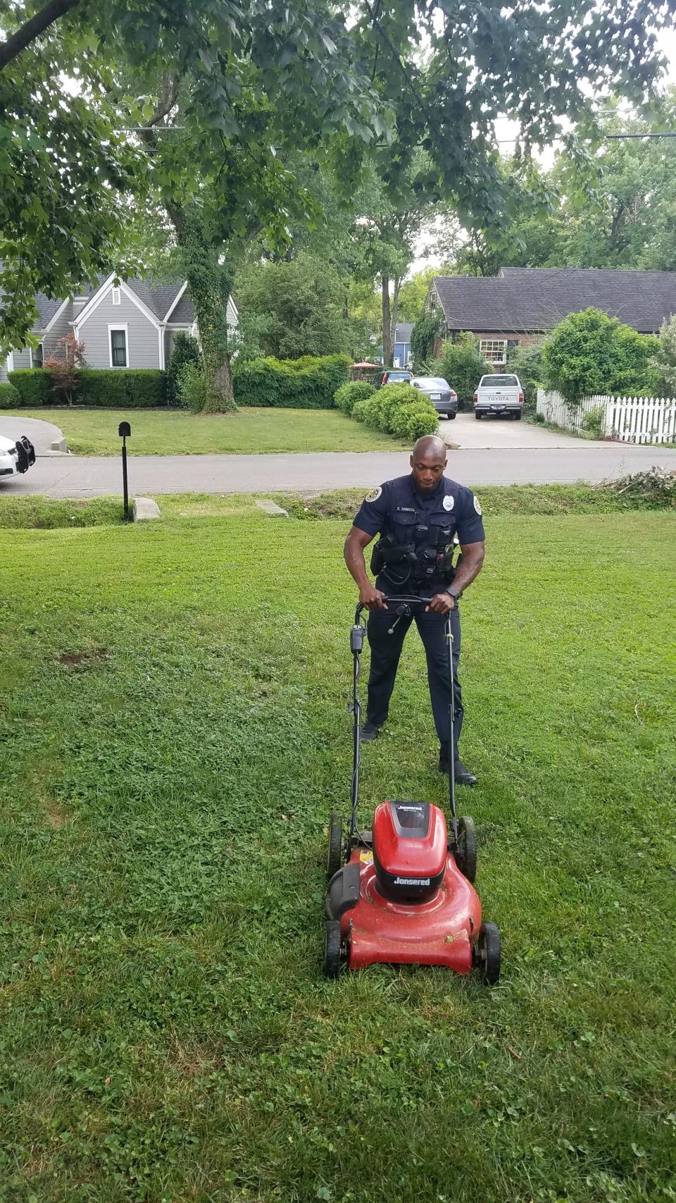 Metro Police Officer Sekou Samassi finishes cutting the grass July 4, 2022, for a 75-year-old widow in the Green Hills area after answering a call at her house for an alarm going off